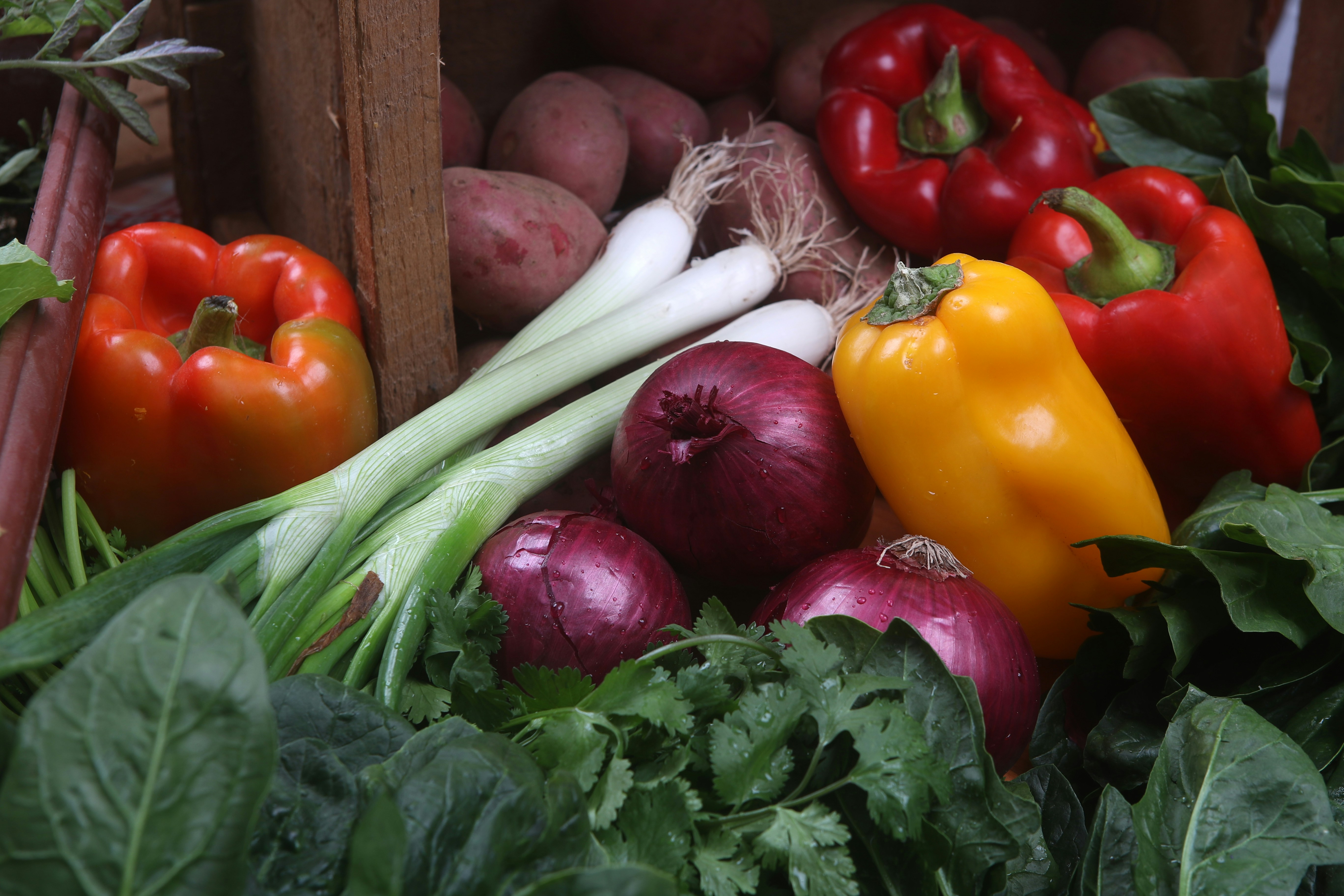 Fresh organic vegetables including carrots, cauliflower and green chilies on wooden crate