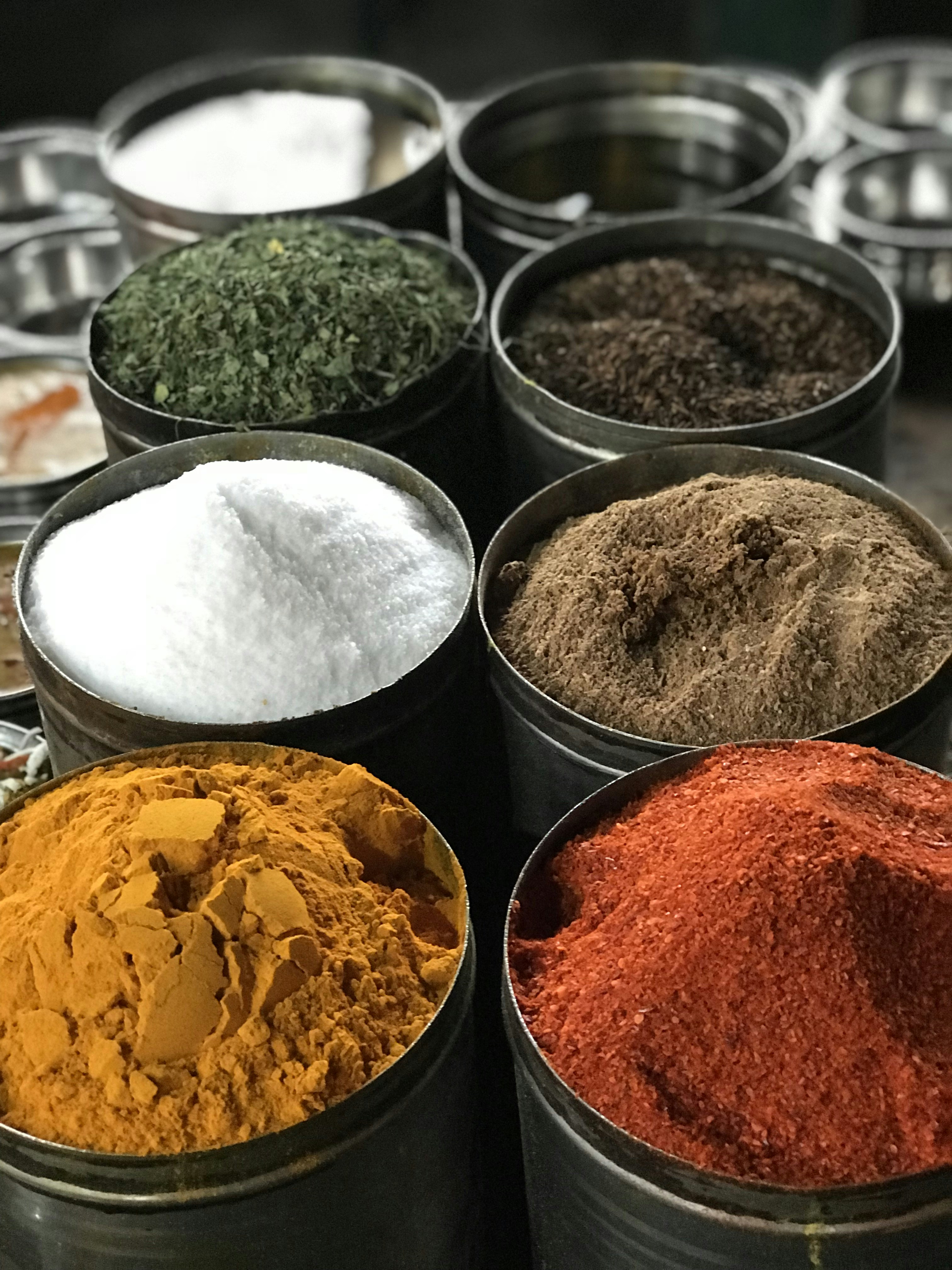 Colorful traditional Indian spices in wooden bowls including turmeric, red chili and mustard seeds